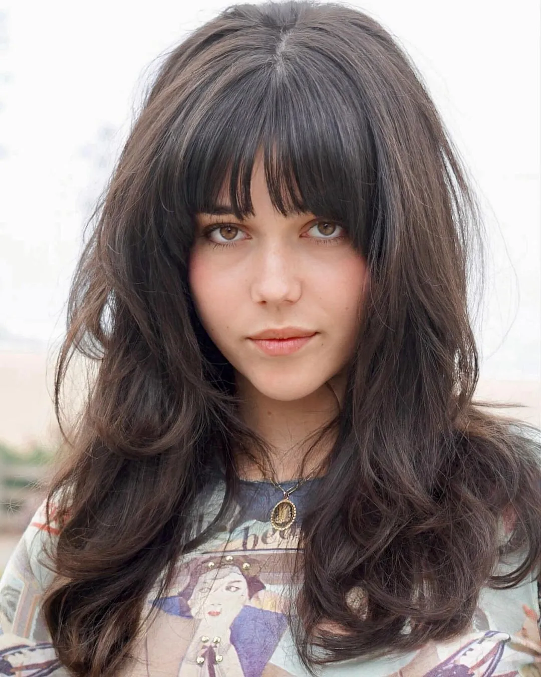 Long Feathered Curly Haircut for an Oval Face with Full Bangs